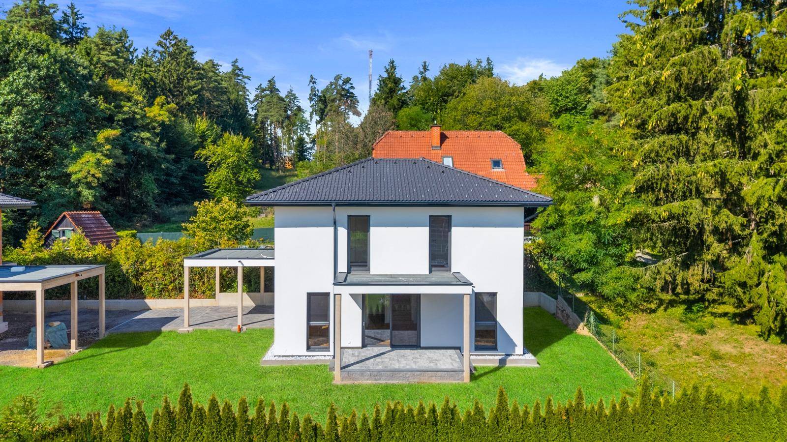 Vorderansicht eines modernen Einfamilienhauses mit weißer Fassade und Carport.