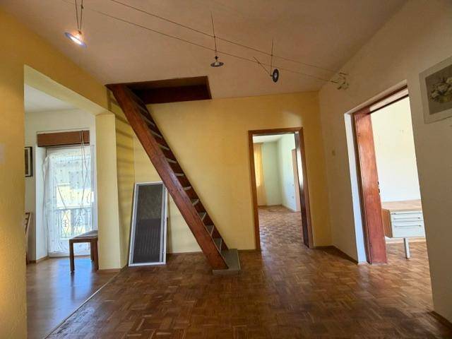Flur mit Holzparkett und einer steilen Holztreppe, die in ein Obergeschoss führt.