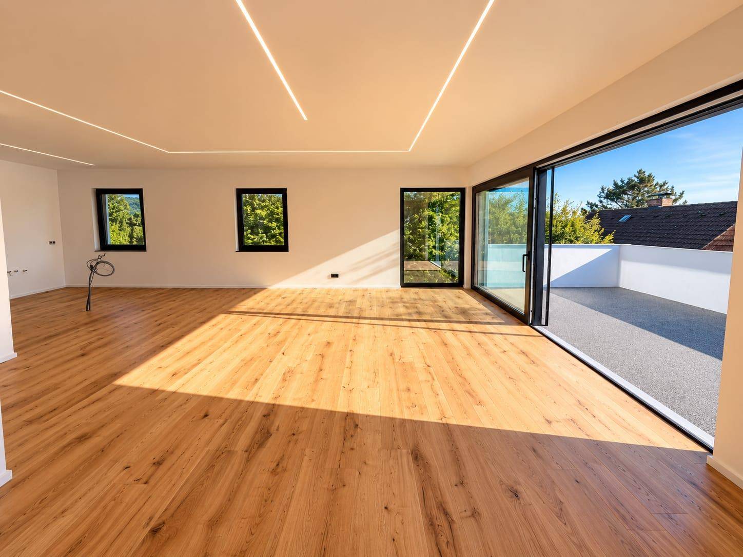 Heller, geräumiger Wohnbereich mit Holzboden, großen Fenstern und direktem Zugang zur Terrasse.