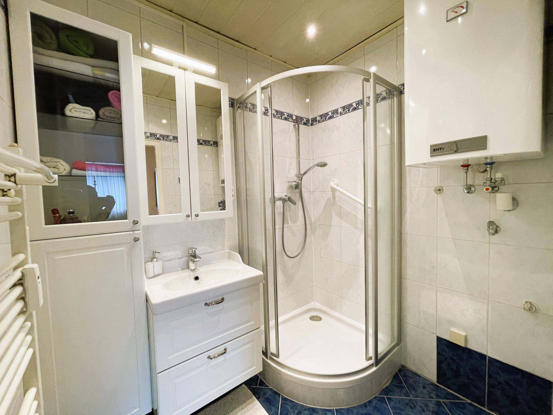 Badezimmer mit Duschkabine, Waschbecken und beheiztem Handtuchhalter.