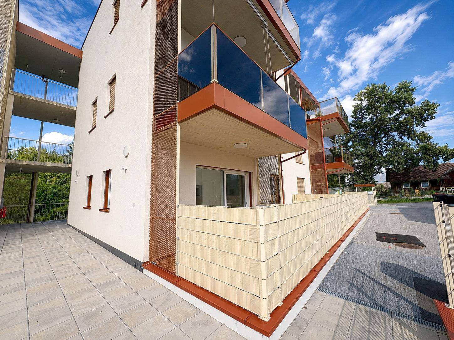 Moderne Architektur des Gebäudes mit Balkonen, Terrassen und gepflasterten Außenbereichen.