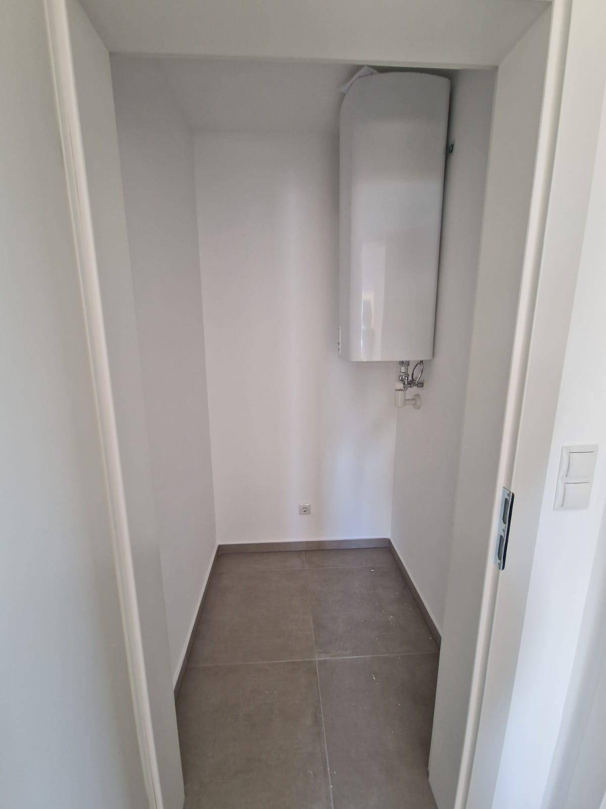 Praktischer Abstellraum mit Fliesenboden und einem Warmwasserboiler an der Wand.