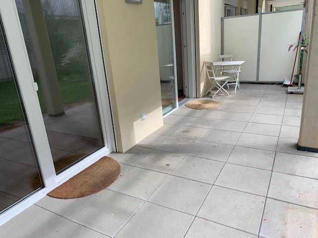 Geräumige geflieste Terrasse mit kleinem Tisch und Stühlen, ideal für Entspannung im Freien.