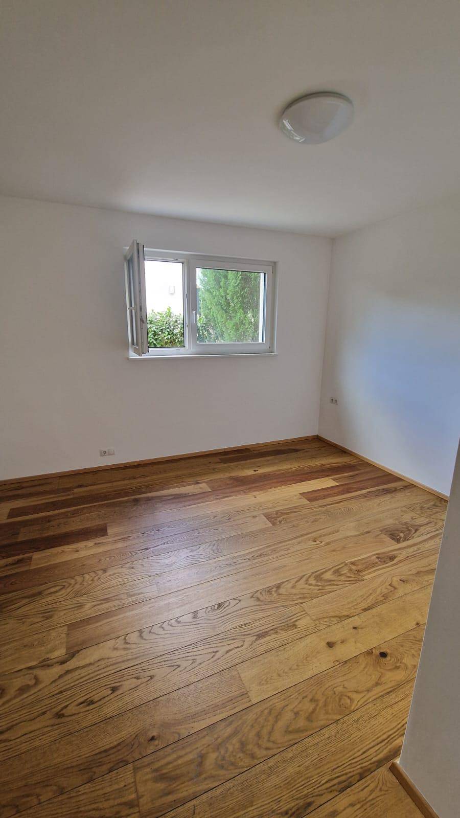 Gemütliches Schlafzimmer mit Holzboden und Deckenleuchte, bereit zur individuellen Gestaltung.