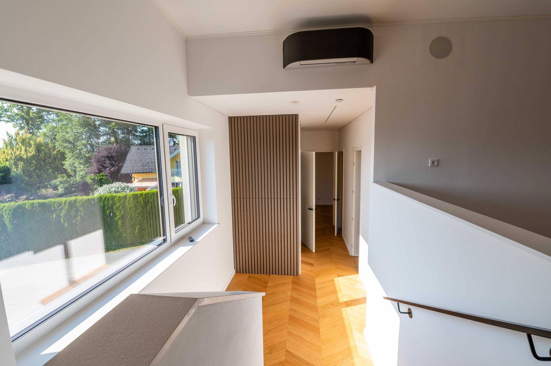 Heller Flurbereich im Obergeschoss mit großem Fenster und Klimaanlage.