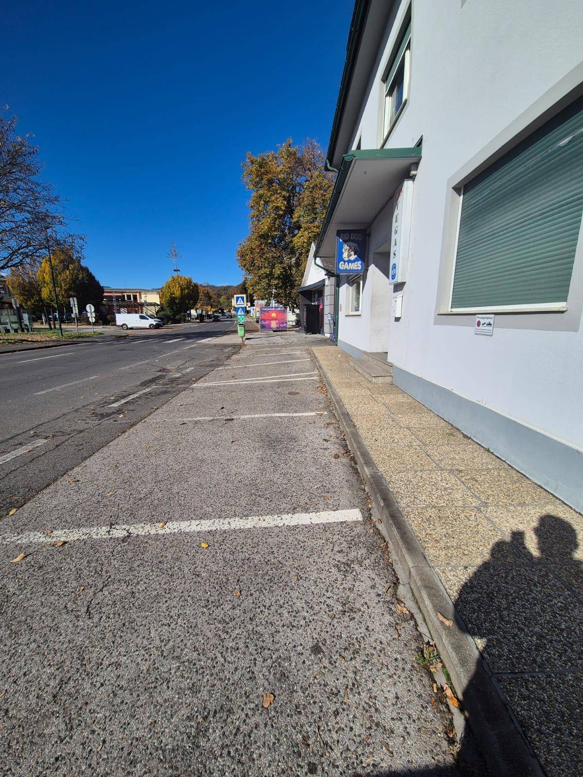 Straßenansicht entlang des Gebäudes mit Bürgersteig und einer Rampe zum Eingangsbereich.