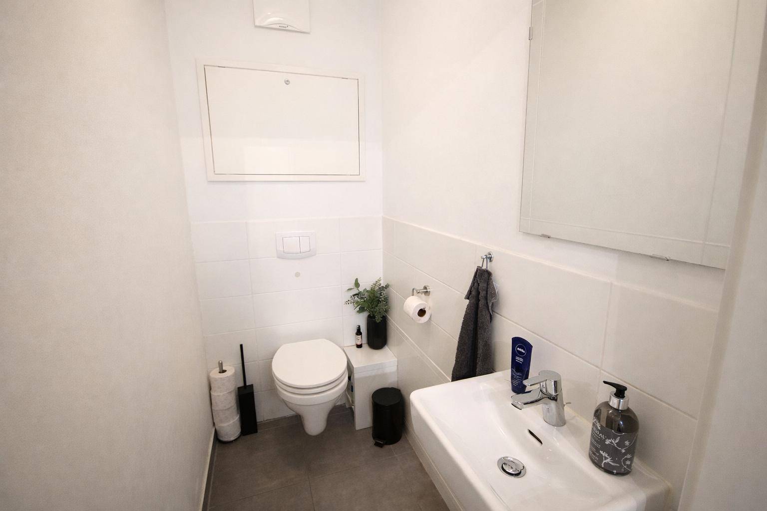 Separates Gäste-WC mit Waschbecken und Toilette, hell gefliest und funktional.