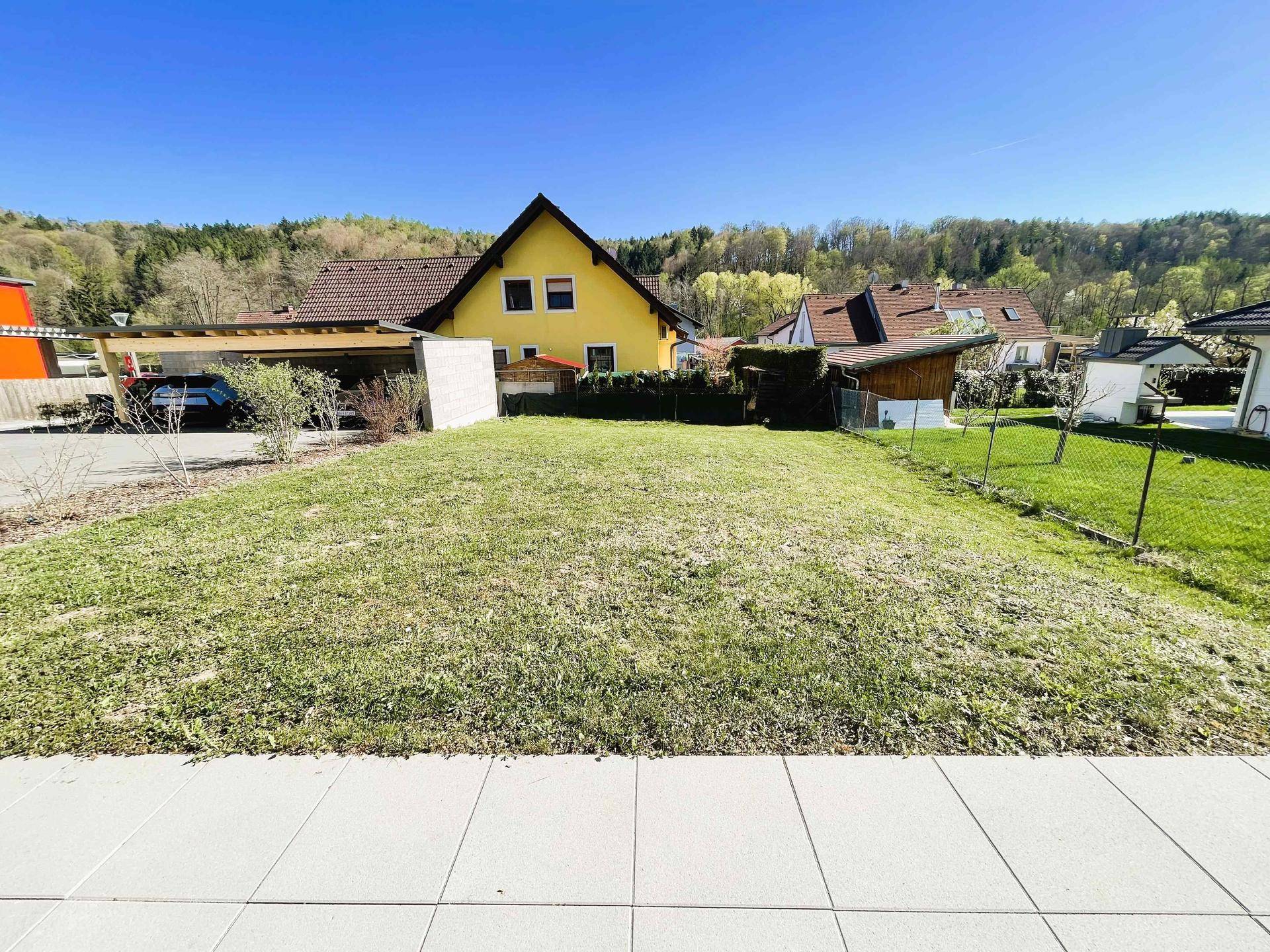 Grüne Rasenfläche im Gartenbereich eines Wohnhauses mit Blick auf die umliegende Landschaft.