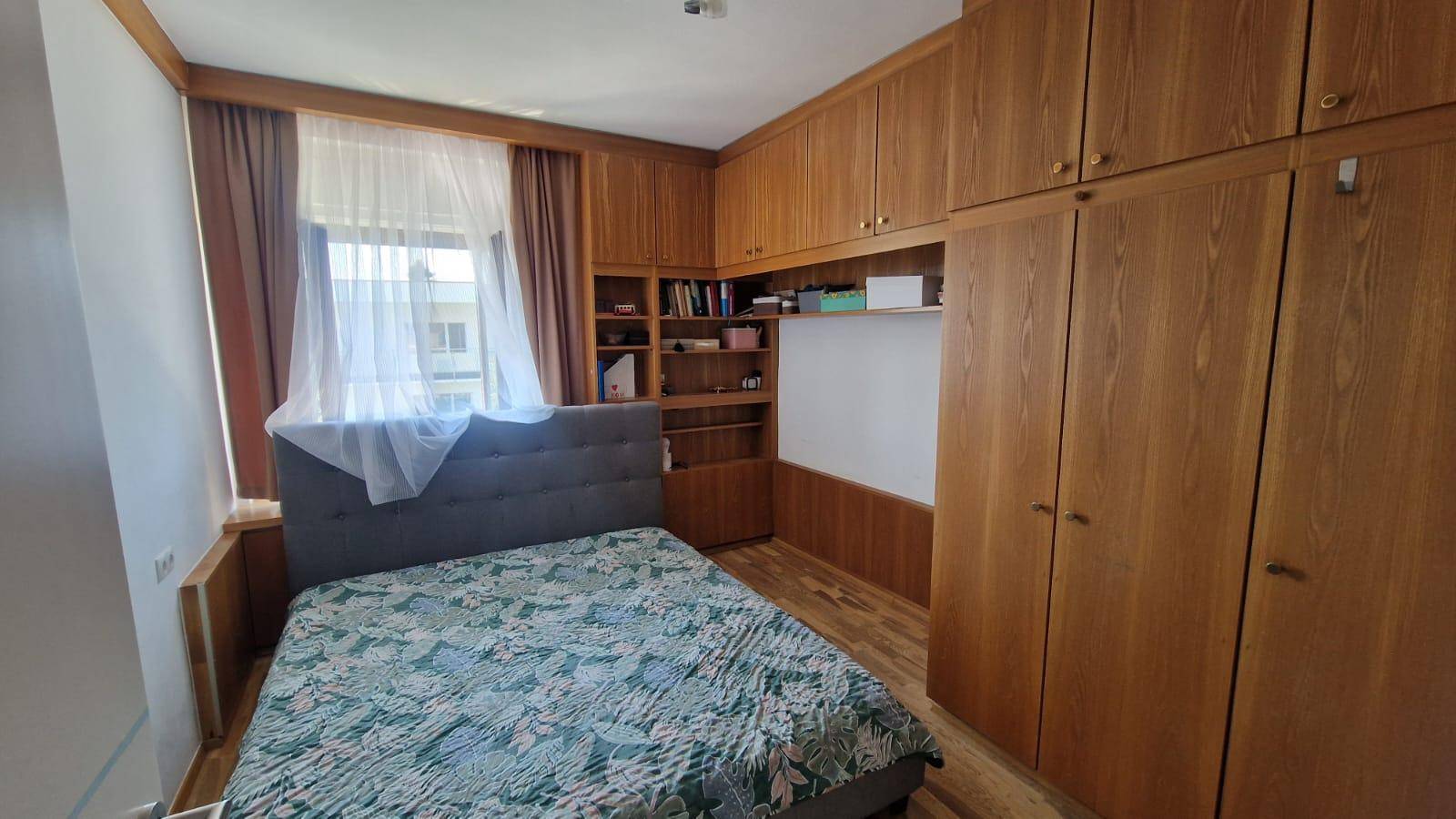 Schlafzimmer mit Doppelbett, eingebauten Holzschränken und Fenster, bietet viel Stauraum.