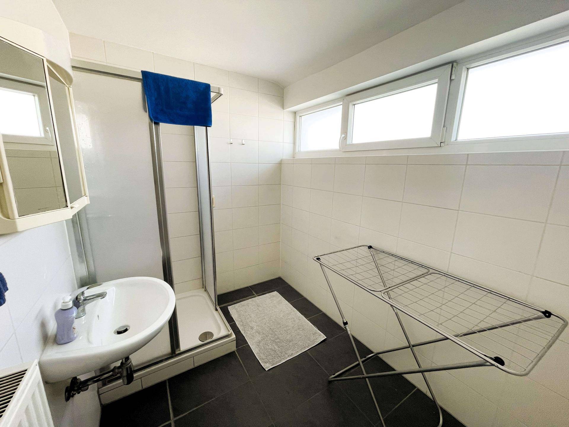 Badezimmer mit Duschkabine, Waschbecken und Fenster, in funktionalem Design.
