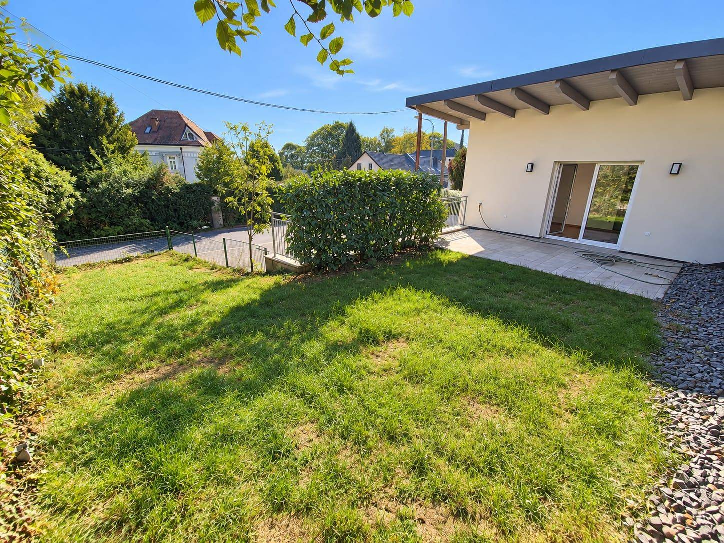 Gepflegter Rasenbereich mit kleiner Terrasse und Hecke, ideal für Entspannung im Freien.