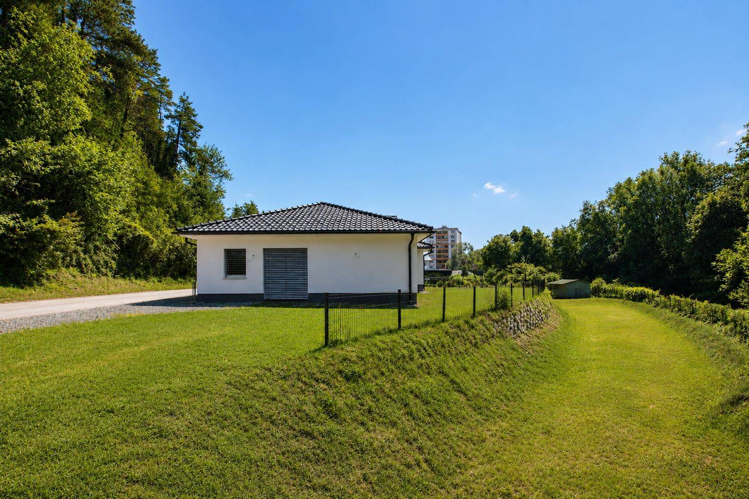 Rückansicht des Bungalows mit großem Rasenbereich und Blick auf die umliegende Natur.