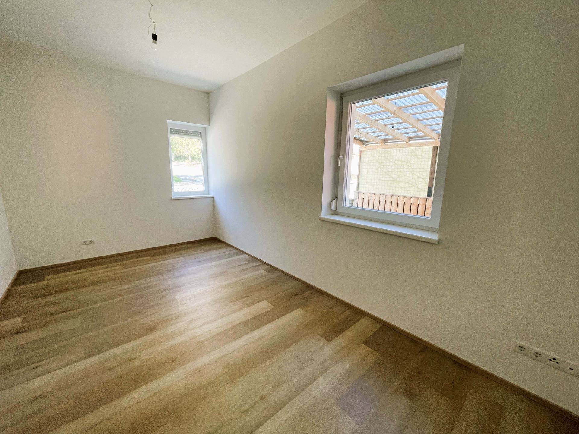 Freundliches Zimmer mit Laminatboden und zwei Fenstern für gute Belichtung.