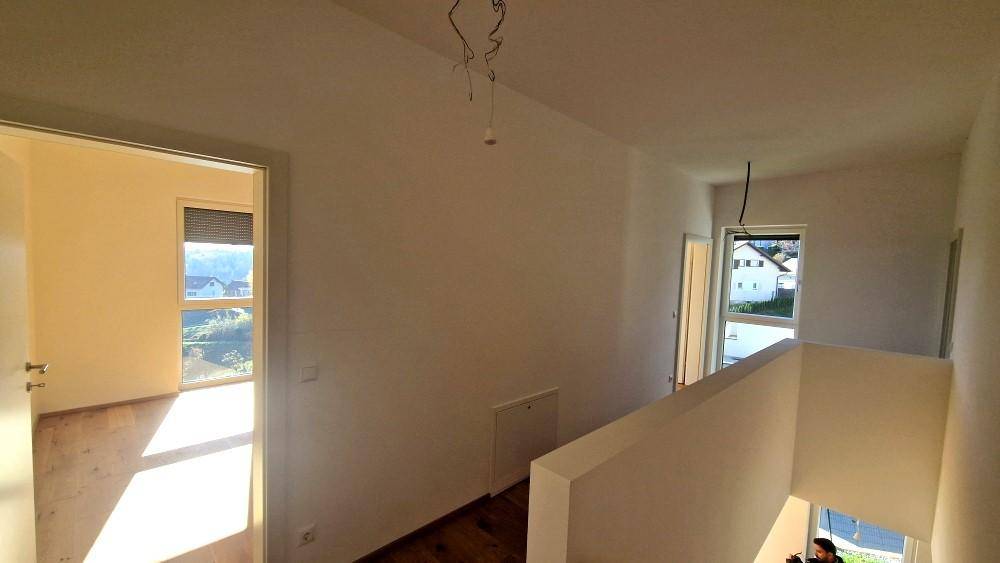 Heller Flur im Obergeschoss mit Holzboden und Zugang zu mehreren Zimmern, mit Blick nach draußen.