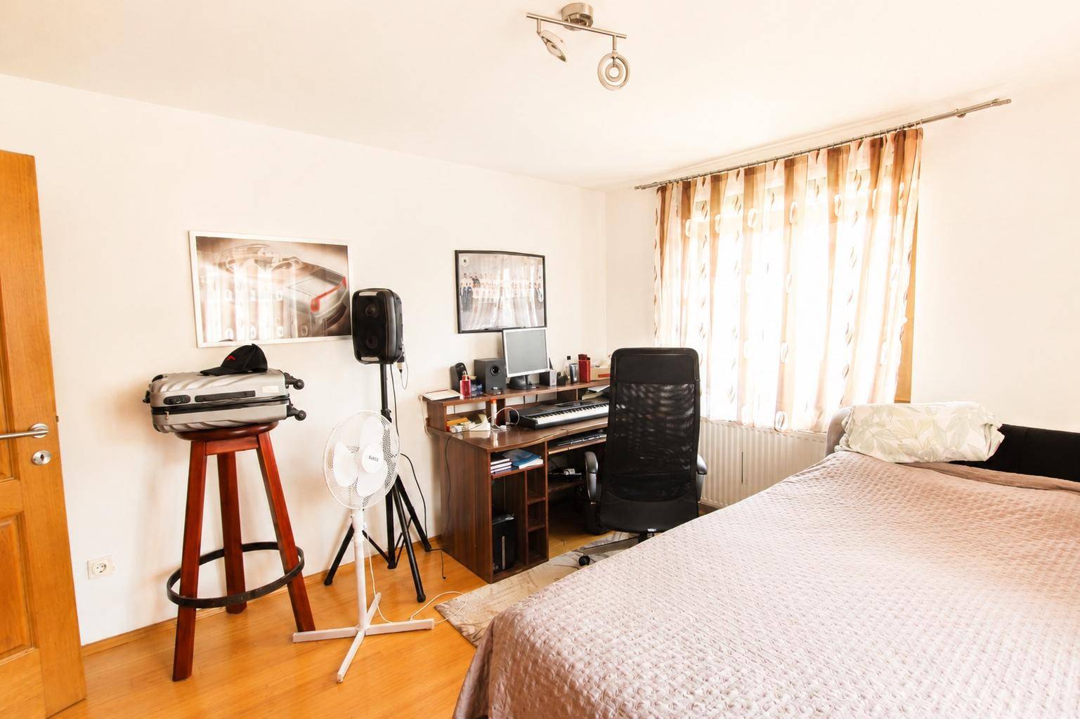 Geräumiges Schlafzimmer mit Schreibtisch, Computer-Setup und einem bequemen Bett.