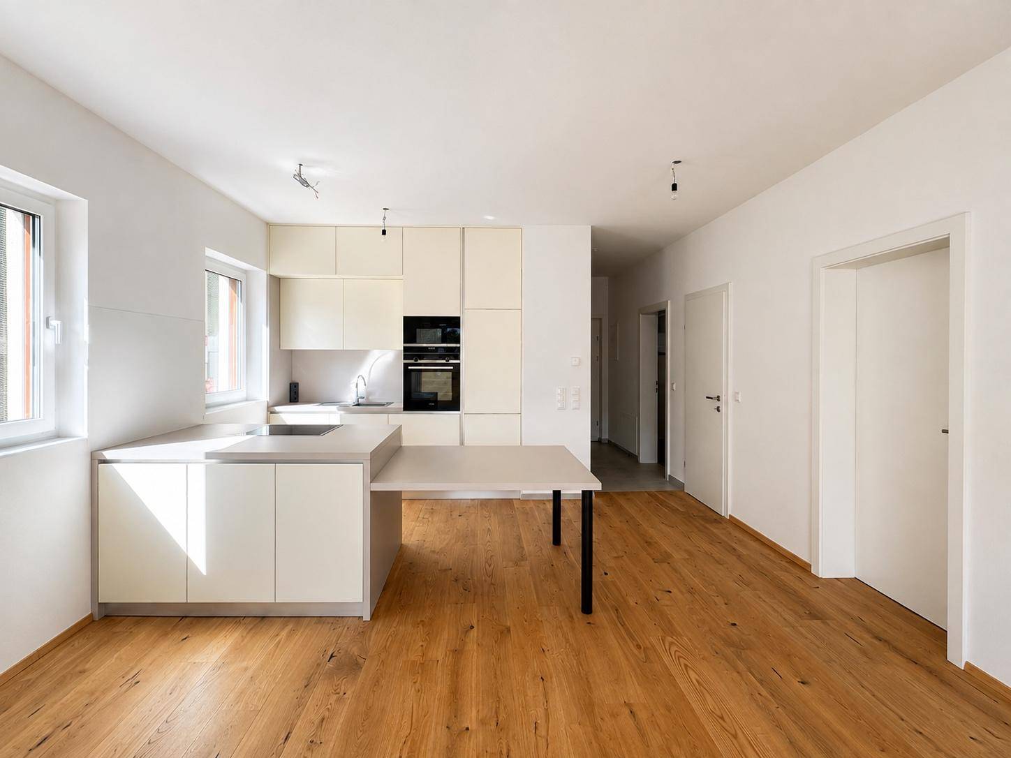 Offene, helle Küche mit modernen Einbauschränken und hochwertigem Holzboden.