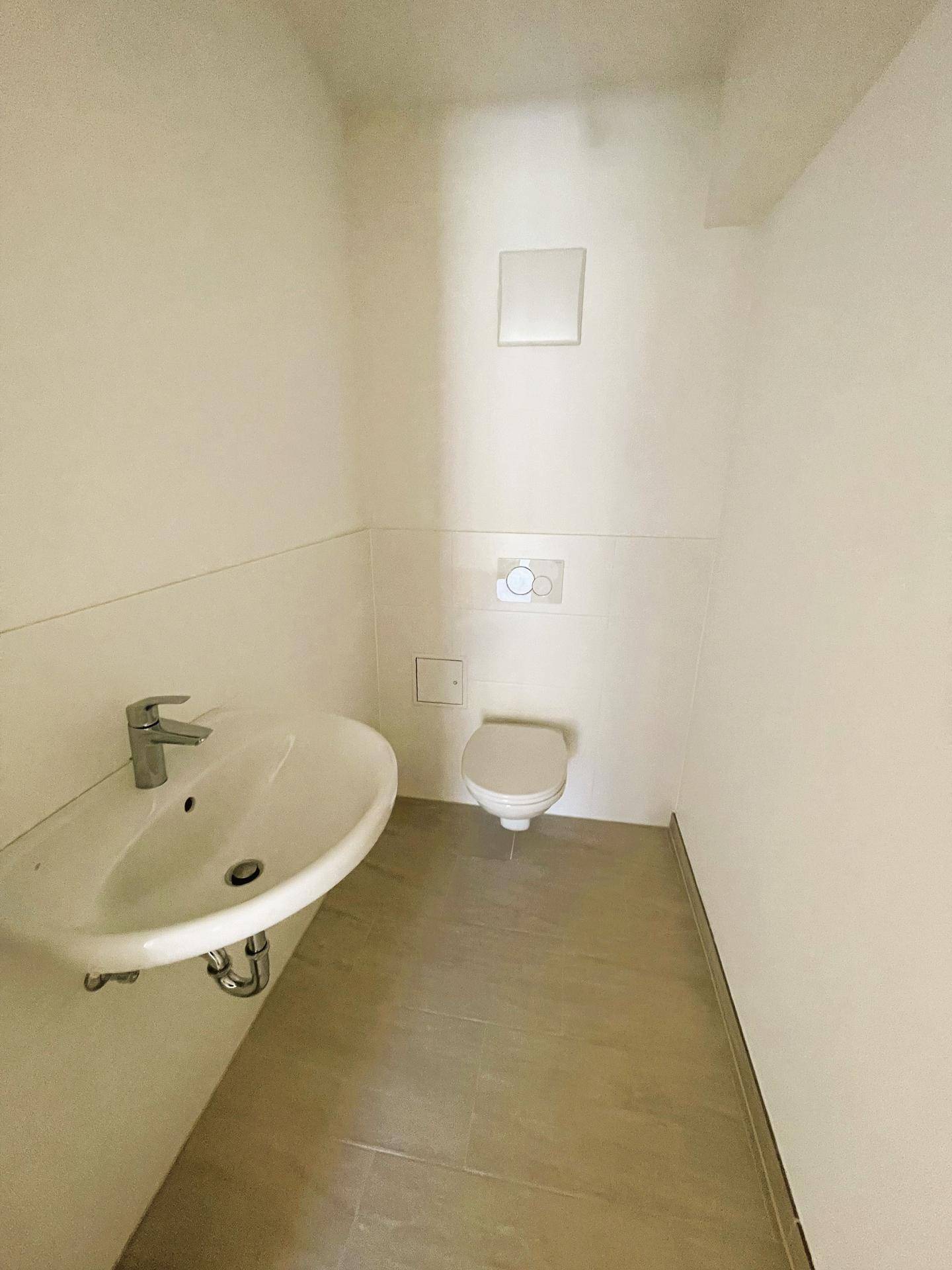 Modernes Gäste-WC mit Wand-WC und kleinem Waschbecken in minimalistischem Design.