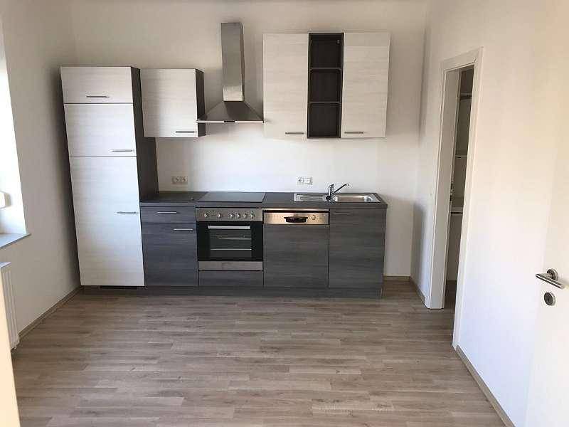 Moderne Einbauküche mit grauen und weißen Schränken, Induktionskochfeld und Dunstabzugshaube.