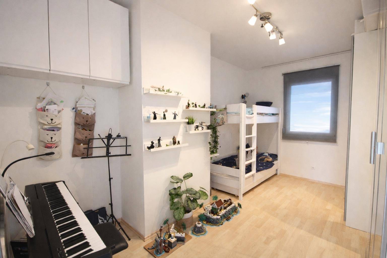 Kinderzimmer mit Etagenbett, Spielzeug und Musikinstrument, hell und freundlich gestaltet.