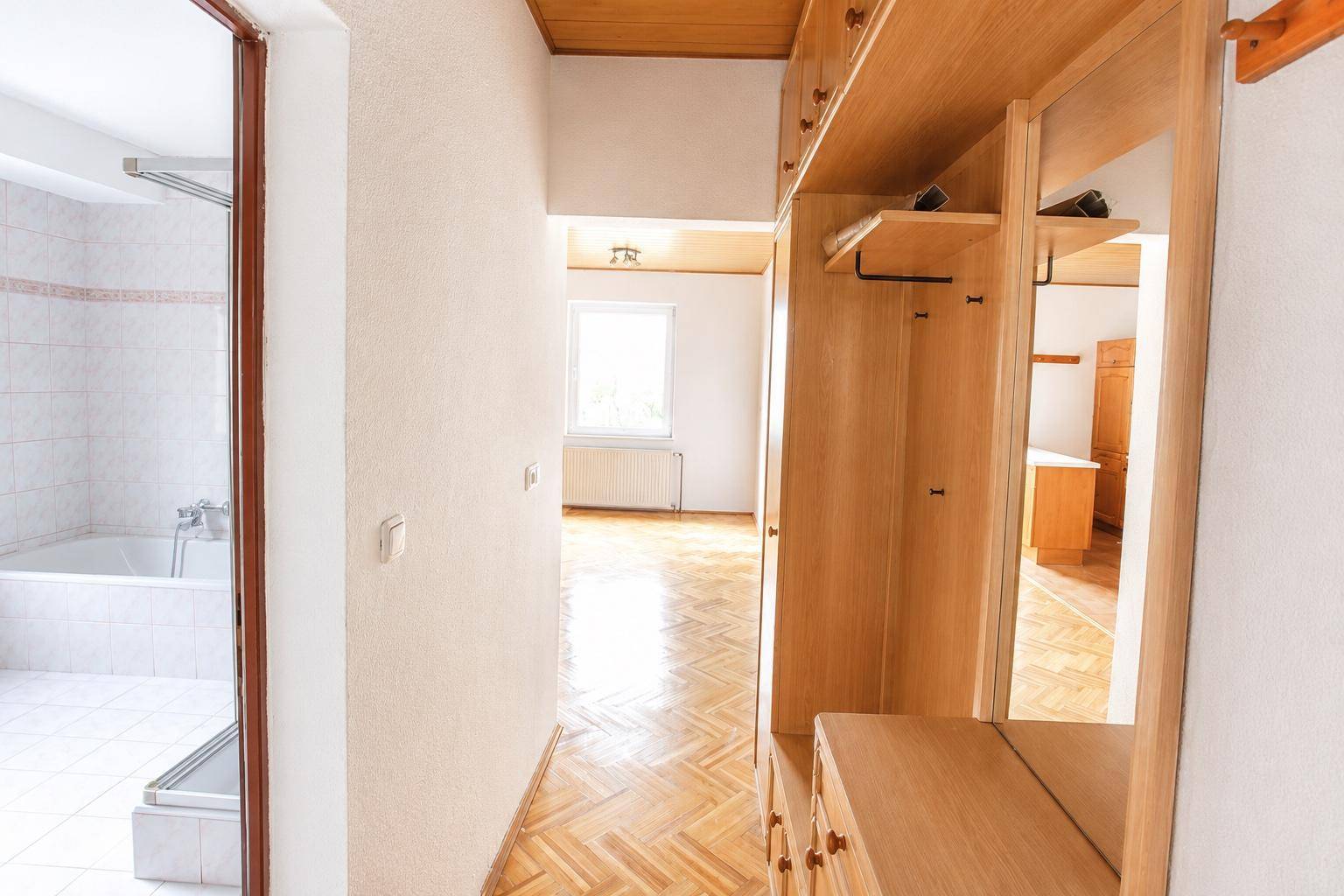 Flur mit Holzparkett, Einbauschränken und Zugang zu einem Badezimmer und weiteren Räumen.