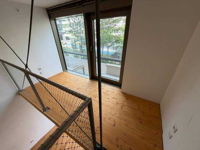 Galeriebereich mit großen Fenstern, die viel Tageslicht hereinlassen und einen Blick ins Grüne bieten.