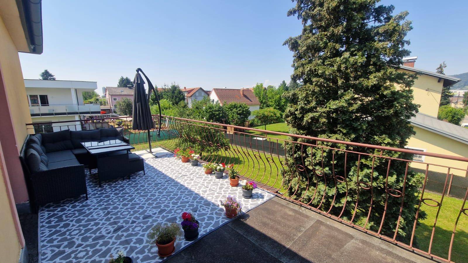 Große Terrasse mit Outdoor-Möbeln, Pflanzen und Blick auf den Garten und die Umgebung.