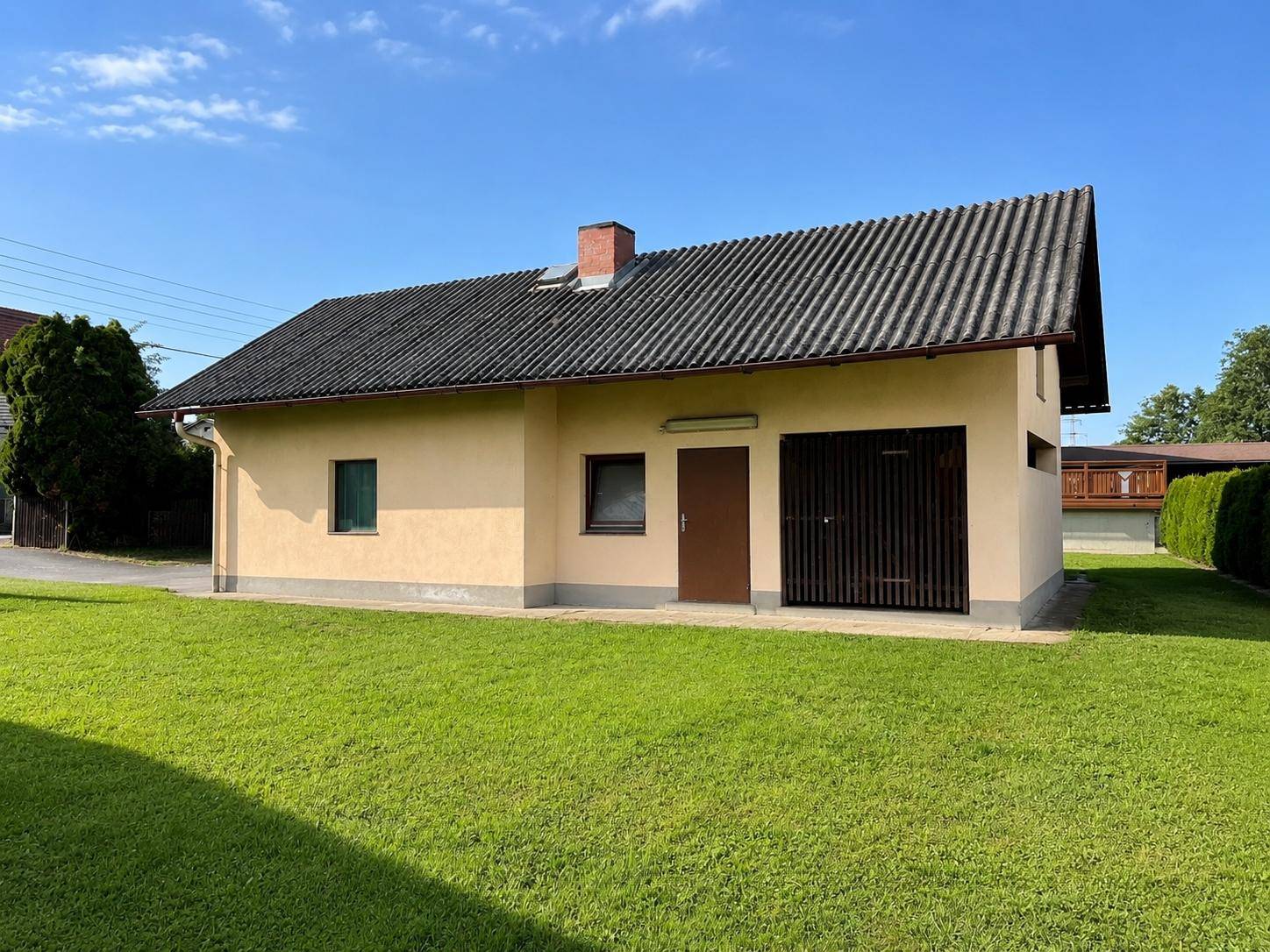 Nebengebäude mit Garage und separatem Eingang, umgeben von einer grünen Rasenfläche.