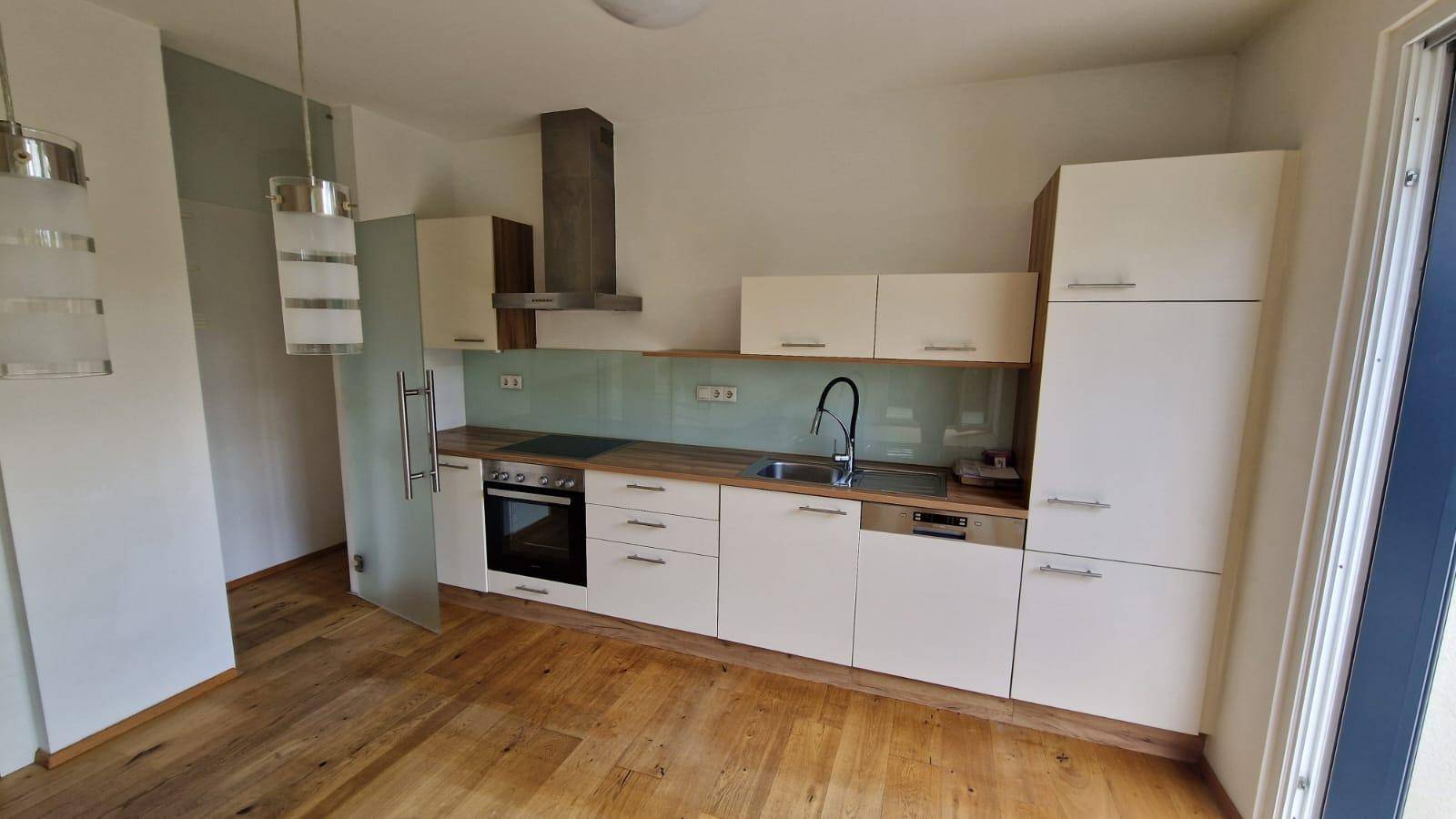Moderne Einbauküche mit hellen Fronten, Holz-Arbeitsplatte und integrierten Geräten.