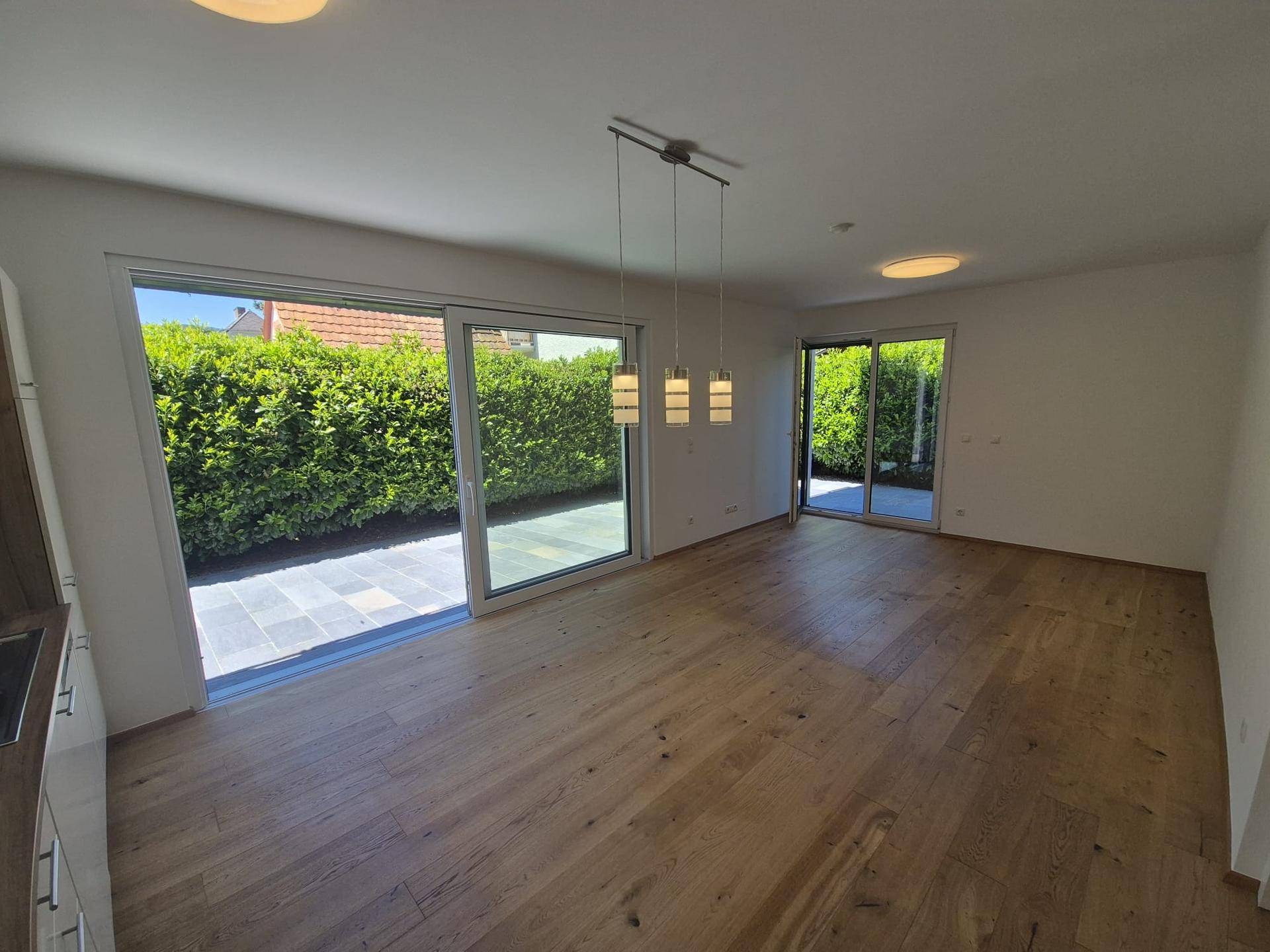Lichtdurchfluteter Wohnbereich mit Holzboden und großen Schiebetüren zur Terrasse.