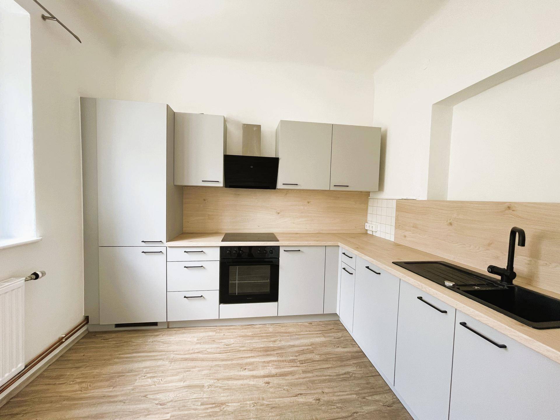 Helle, modernisierte Küche mit grauen Schränken, Holzarbeitsplatte und integrierten Küchengeräten.