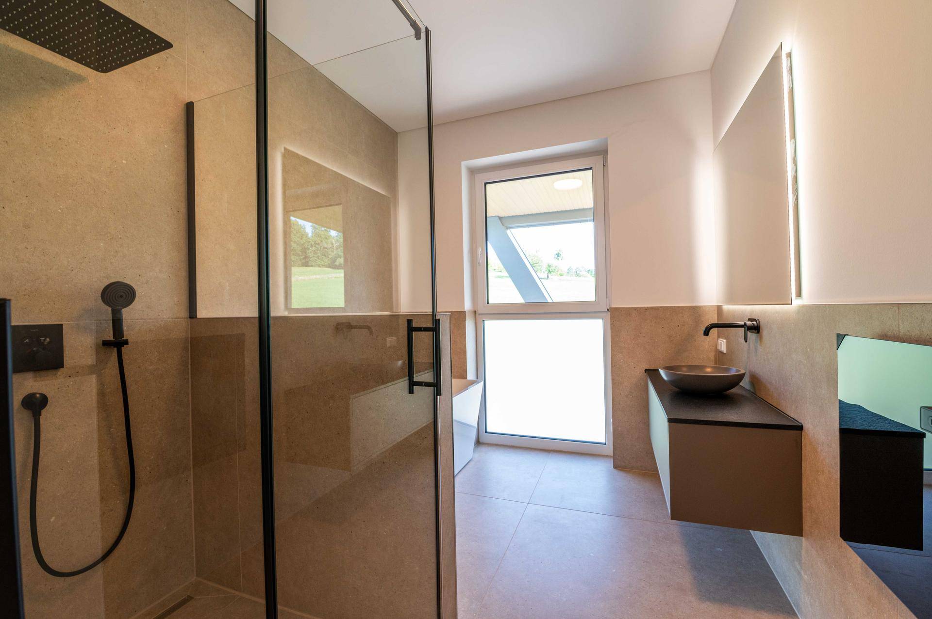 Begehbare Dusche mit Regenduschkopf und Glasabtrennung im modernen Bad.