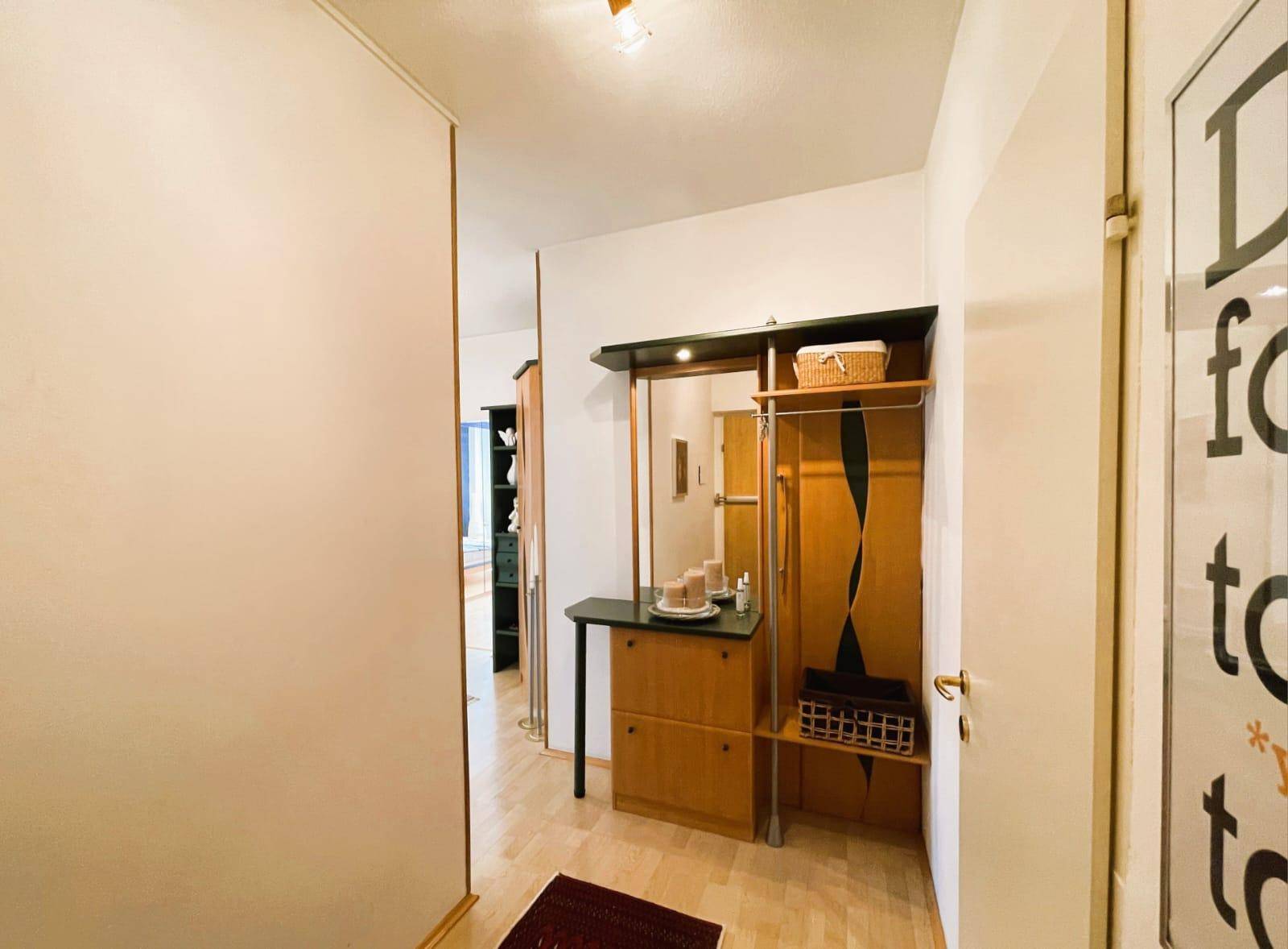 Heller Eingangsbereich mit Garderobe, Spiegel und Holzfußboden.