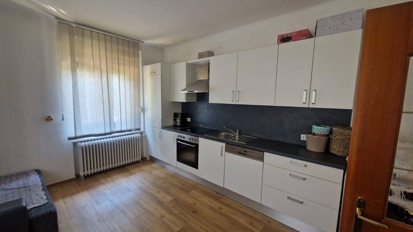 Helle Küche mit Fenster, Heizkörper und funktionaler Ausstattung, ideal für den täglichen Gebrauch.