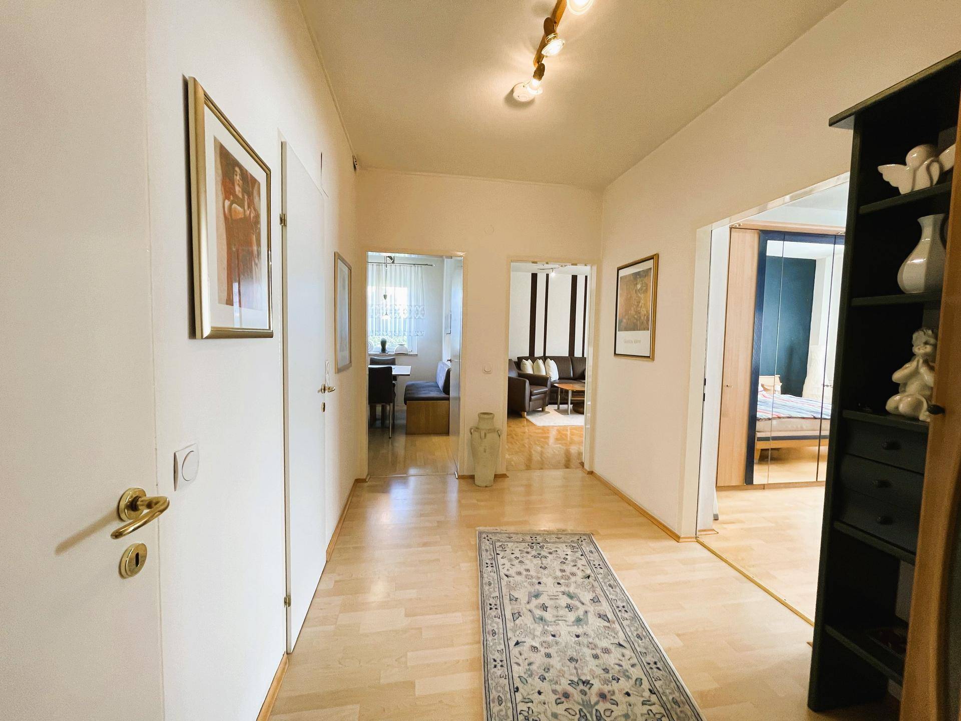 Langer Flur mit hellem Parkettboden, der zu verschiedenen Zimmern der Wohnung führt.