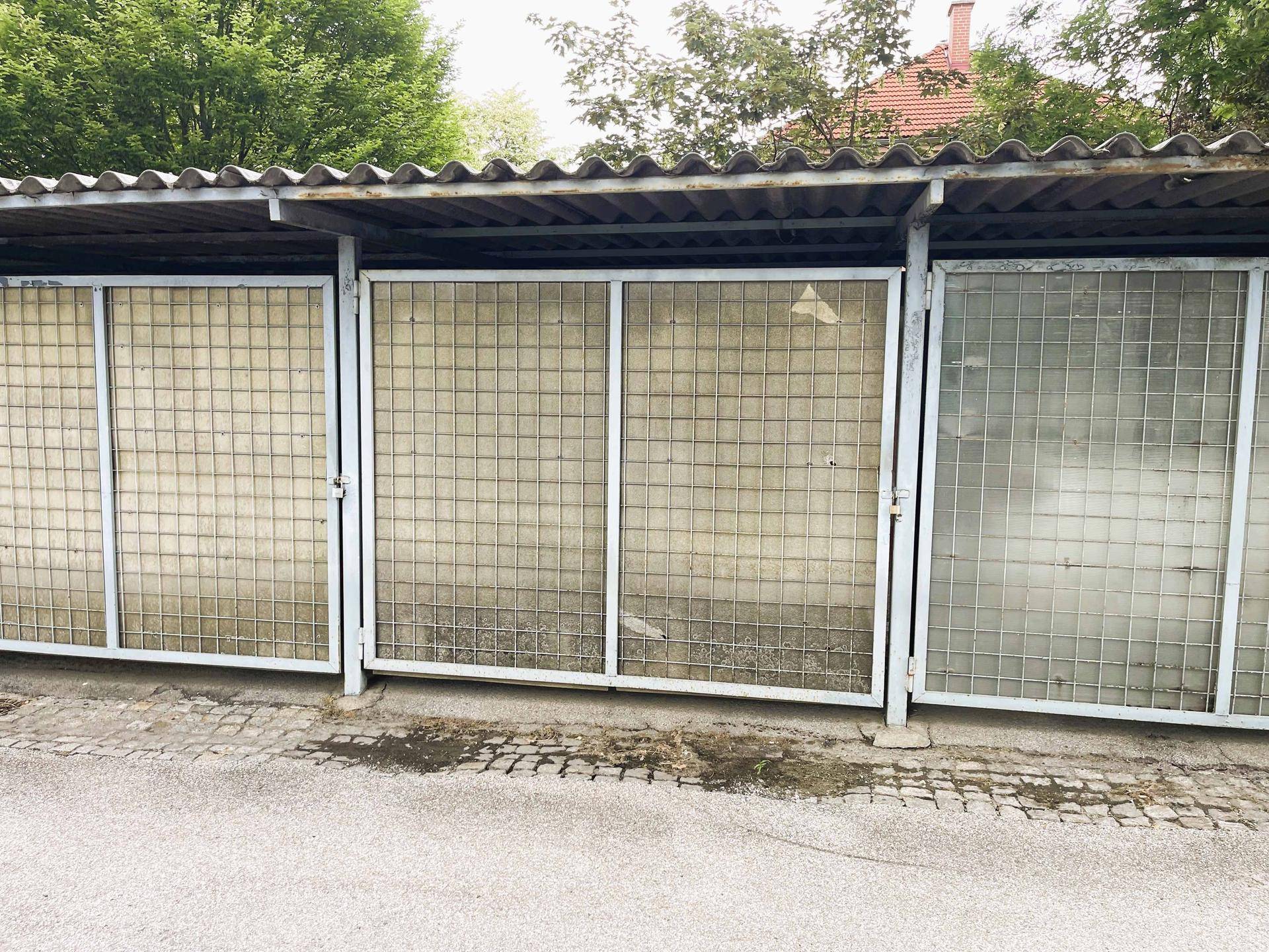 Außenlagerbereiche mit Gittertüren, möglicherweise für Fahrräder oder Abstellzwecke.