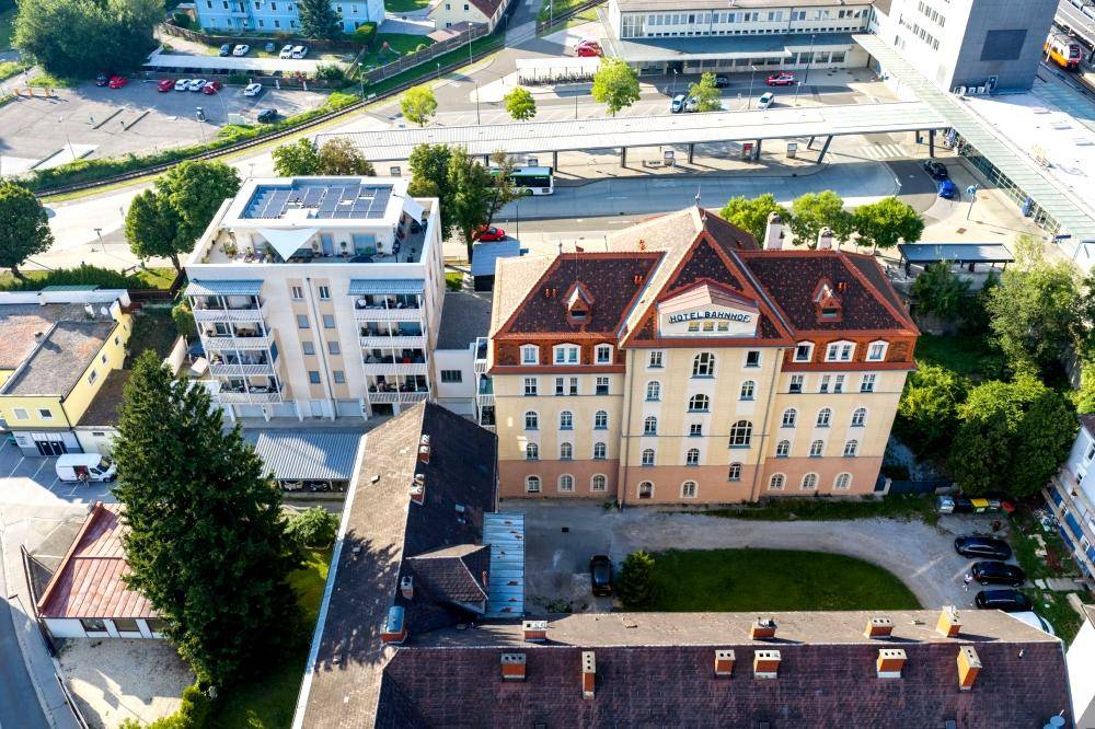 Luftaufnahme von zwei Gebäuden, einem historischen Hotel und einem modernen Wohnhaus mit Solaranlage.