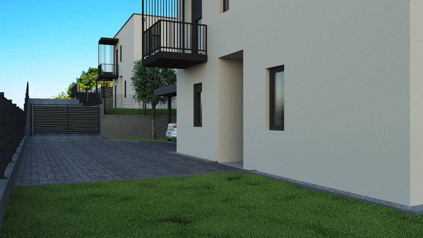 Einfahrt mit Pflastersteinen und gepflegtem Rasen vor der modernen Hausfassade.