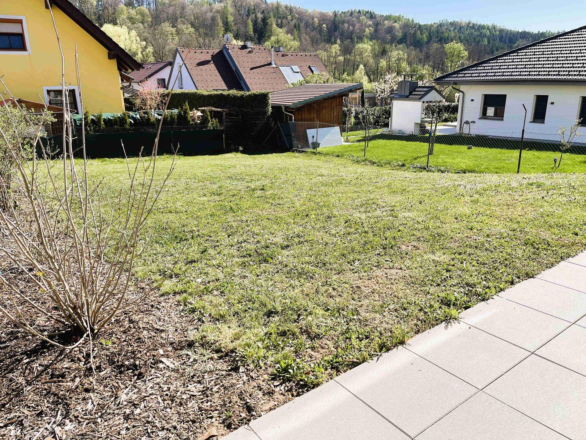 Großer Gartenbereich mit Rasen und Blick auf die ländliche Umgebung und Nachbarhäuser.