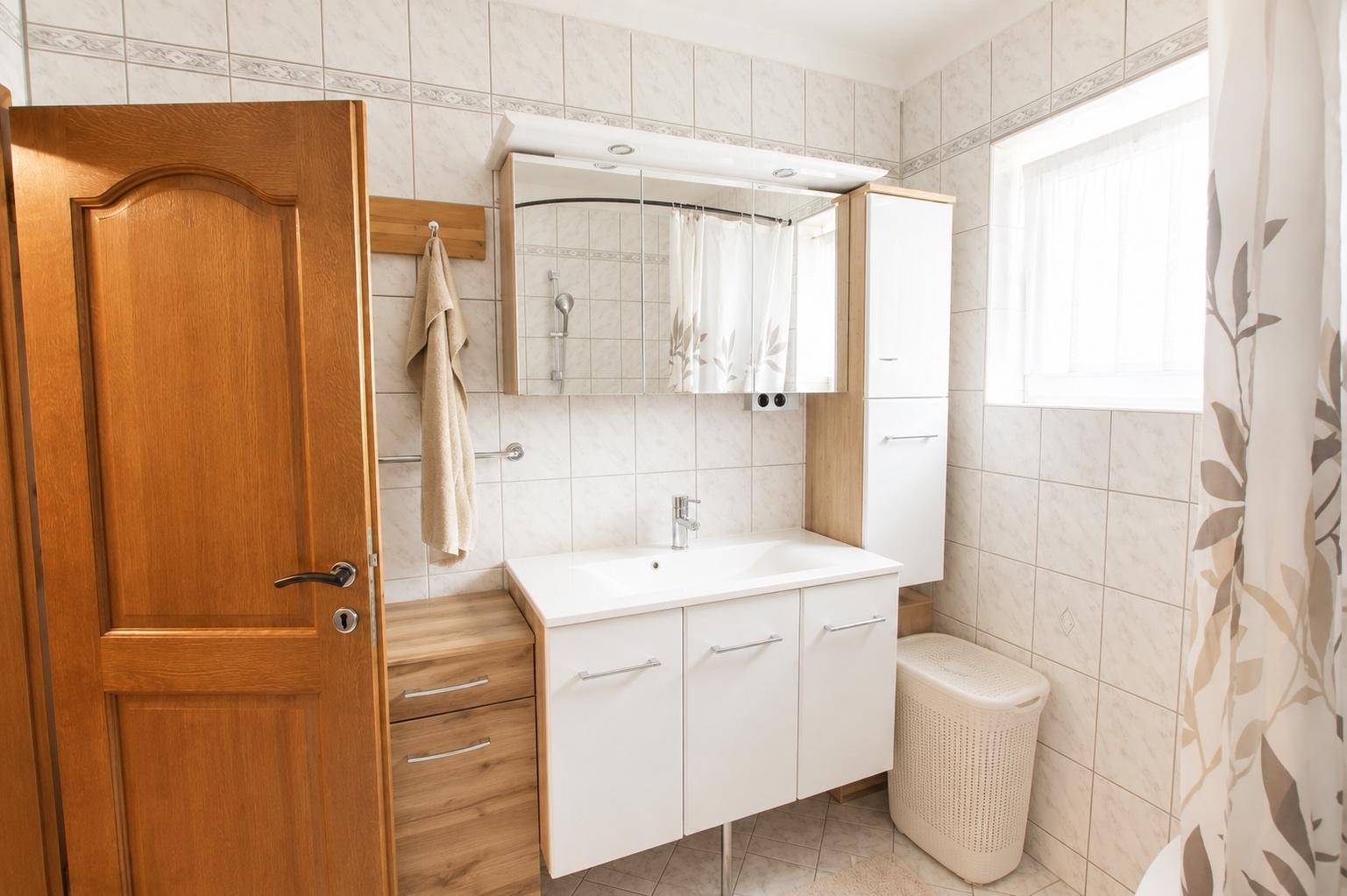 Modernes Badezimmer mit Einzelwaschbecken, Spiegelschrank und Fenster.