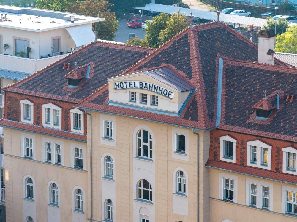Detailansicht des Daches und der oberen Etagen eines historischen Hotels mit "Hotel Bahnhof" Schriftzug.