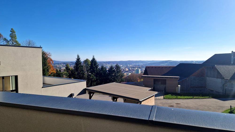 Weitläufiger Ausblick von der Immobilie über die Dächer, Wälder und eine ferne Stadtlandschaft.