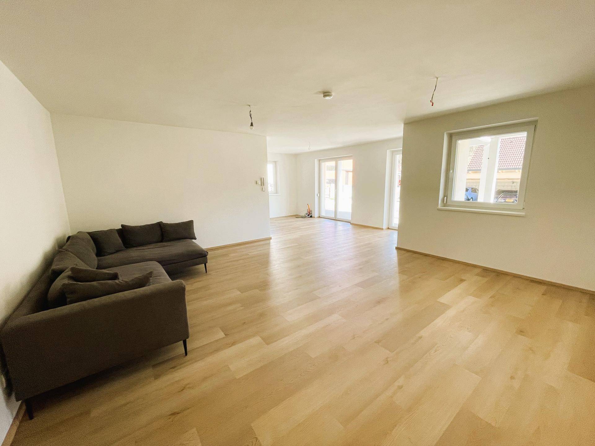 Helles, geräumiges Wohnzimmer mit hellem Holzfußboden und einer modernen Eckcouch.