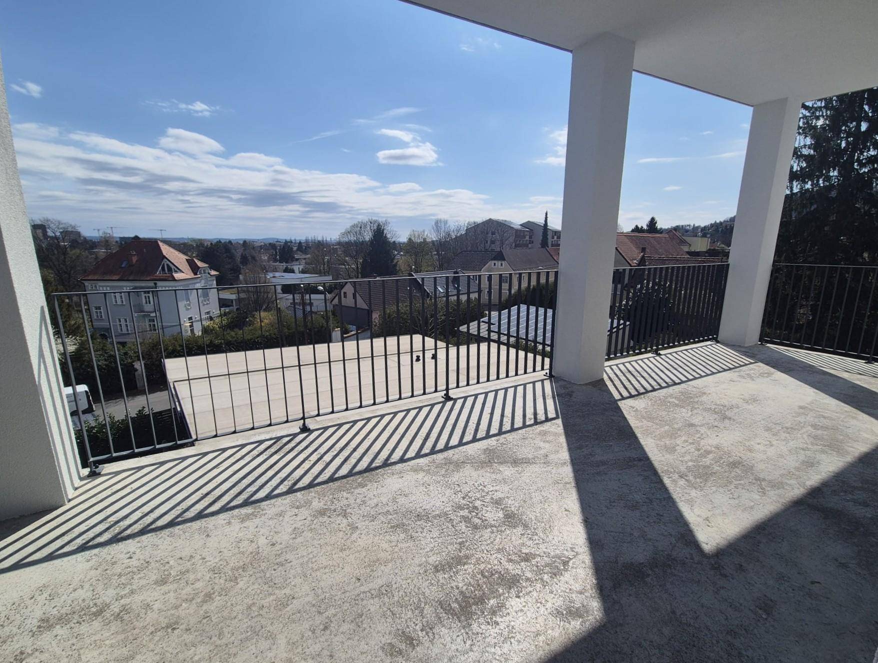 Weitläufige Terrasse mit Betonboden und Metallgeländer, ideal für entspannte Stunden im Freien.