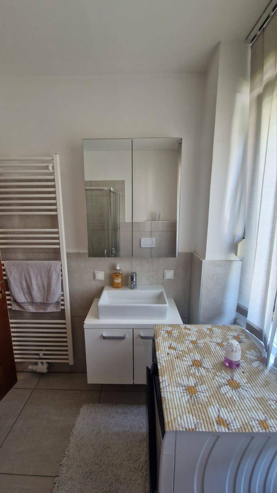 Helles Badezimmer mit Waschbecken, Spiegelschrank und beheiztem Handtuchhalter, modern gefliest.