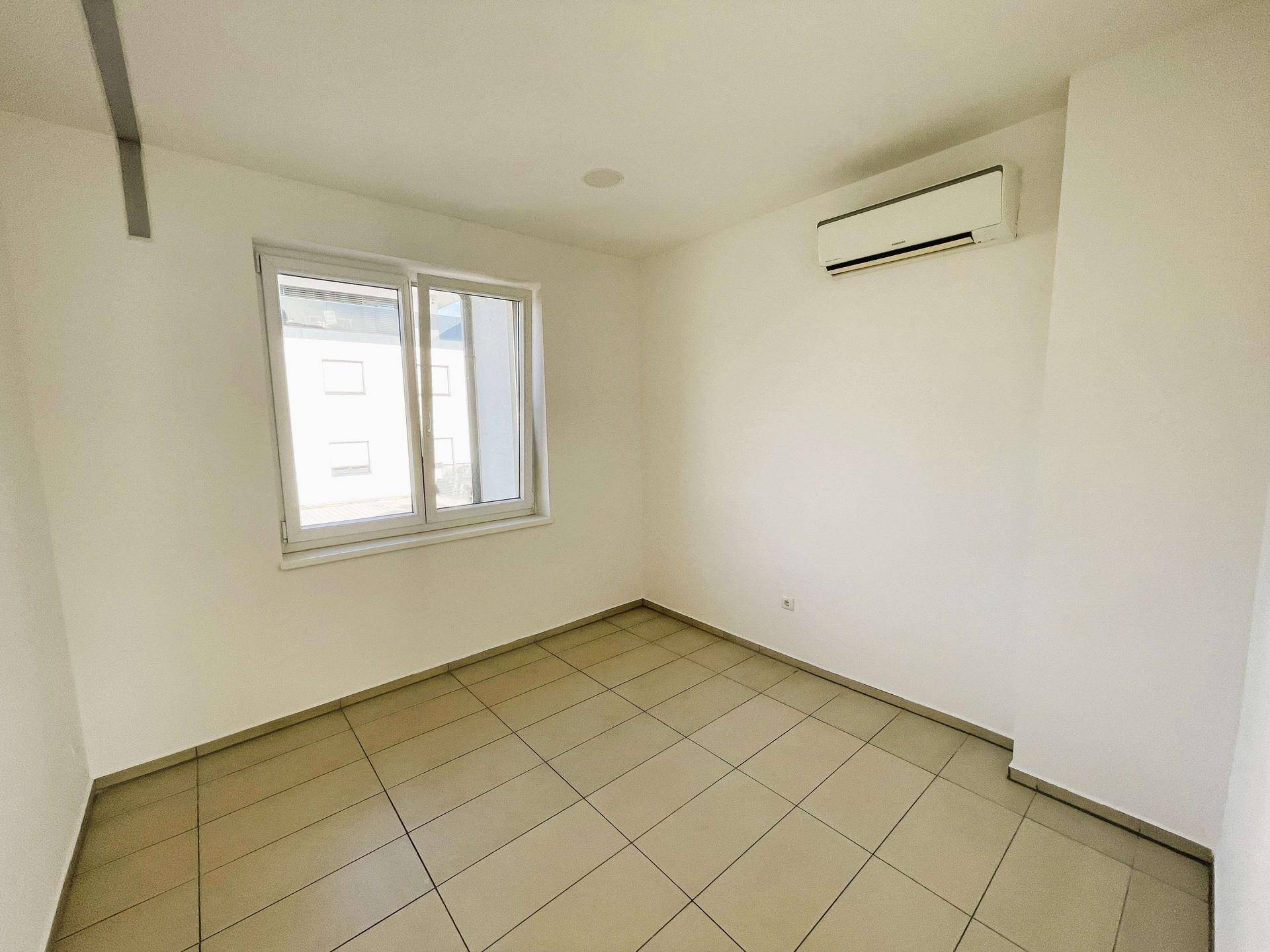 Helles Schlafzimmer mit Fliesenboden, Fenster und Klimaanlage, in gutem Zustand.