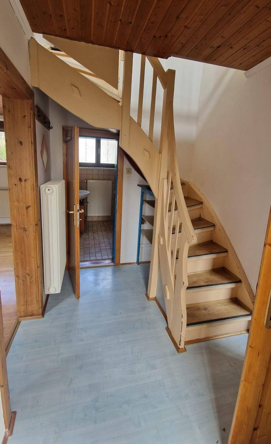 Heller Flur mit einer charmanten Holztreppe, die in die oberen Stockwerke führt.