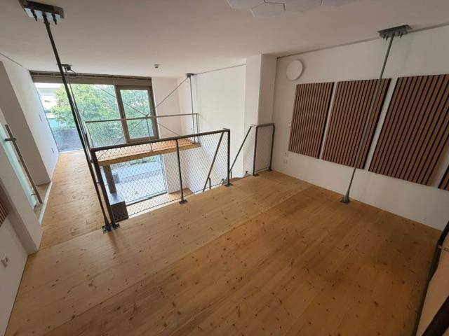 Heller Galeriebereich mit Metallgeländer und großen Fenstern, die den Raum mit Licht füllen.