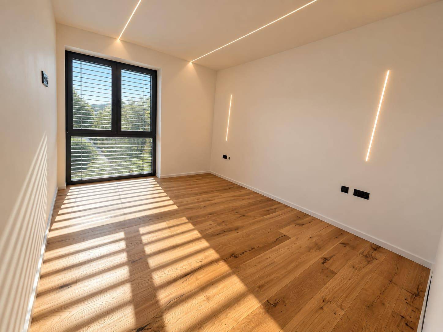 Geräumiges Schlafzimmer mit Holzboden und großem Fenster, das viel natürliches Licht bietet.