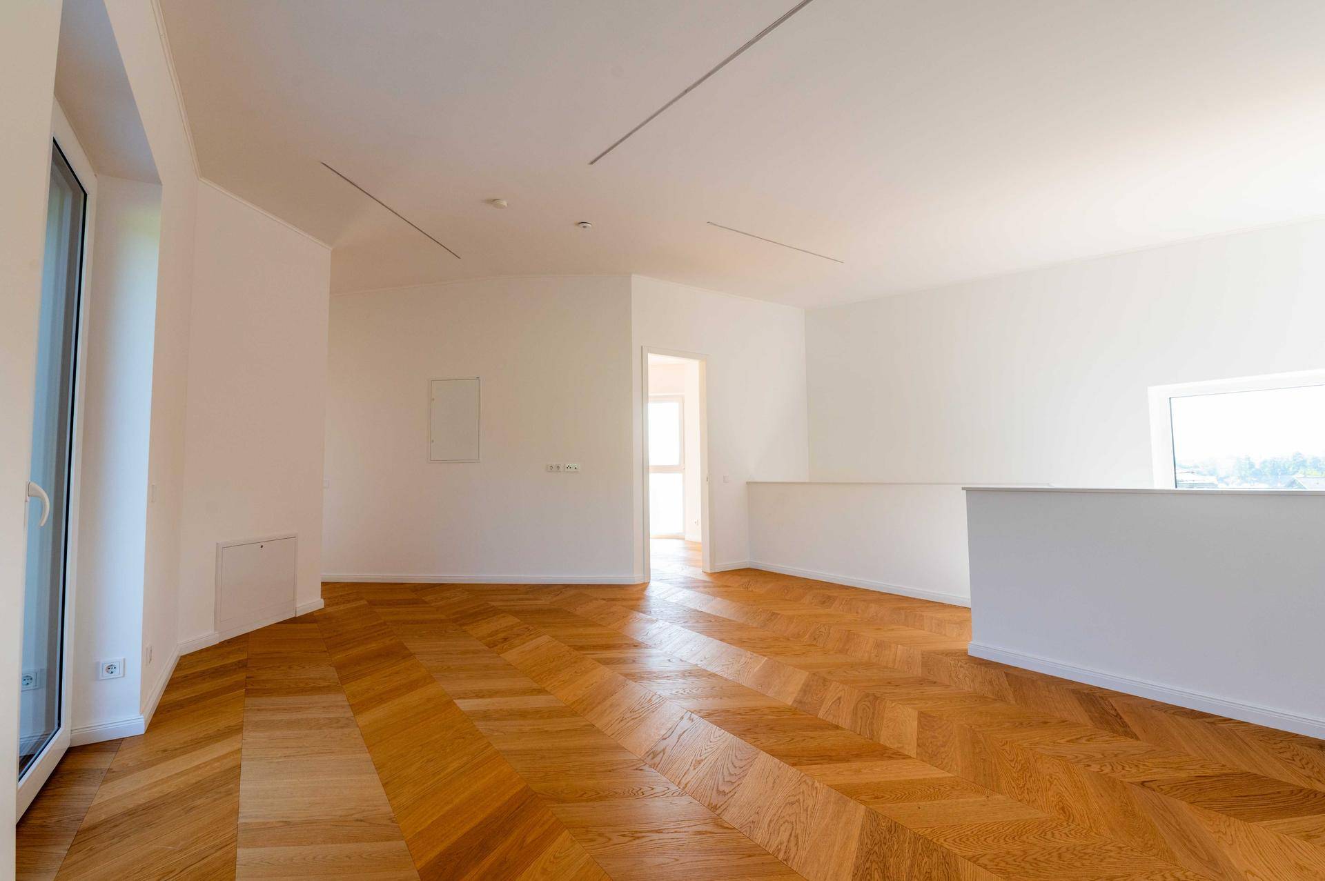 Geräumiger, heller Wohnbereich im Obergeschoss mit Holzboden und weitem Blick.