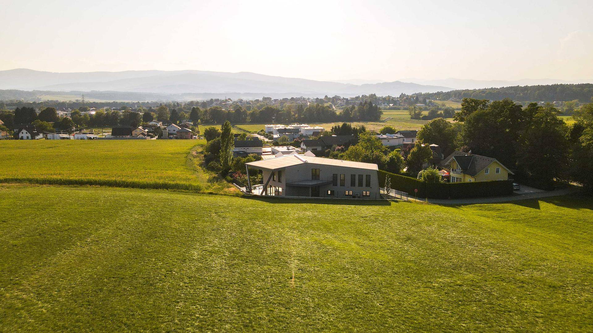 Weitläufige Luftaufnahme der Villa in einer idyllischen Landschaft mit Bergen im Hintergrund.